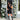 Woman in a black dress and boots standing between floral decorations on a building entrance.