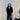 Woman standing in a room with white curtains and a lamp.