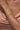 Close-up of a person's arm wearing a gold bracelet with a soft pink fabric background