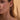 Close-up of a woman wearing gold earrings and a necklace against a beige background