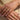 Close-up of hands wearing gold jewelry on a beige background