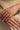 Close-up of hands wearing gold jewelry on a beige background