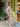 Woman in a beige tracksuit with pink stripes standing outside a store.