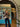 Person taking a mirror selfie in a stylish room with a blue cabinet and clothing rack.