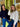 Two women standing in front of a store window, one wearing a navy sweater and blue jeans, the other in a white textured sweater and blue jeans.