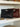Two woven handbags, one black and one brown, on a shelf.