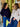 Two women standing and smiling in front of a store window.