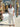 Woman in a white outfit standing in front of a store with floral decorations