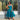 A woman wearing a sleeveless green and blue floral midi dress stands in front of a clothing store window displaying other garments.
