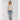 Woman wearing a beige cardigan and blue jeans on a white background