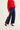 Navy pants with red and white stripes worn with a red sweater on a light background