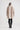 Person wearing a long, light-colored coat with black boots on a white background