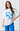 Woman wearing a white t-shirt with blue floral design and text on a plain background