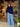 Woman in a blue sweater and jeans standing in a room with a painting and plants.