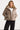 Woman wearing a beige puffer jacket on a white background