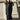 Woman in a black velvet dress standing against a classical building.