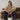 Woman sitting on a brown sofa holding a white bucket with a gold chain.