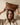 Woman holding a brown leather handbag above her head against a beige background