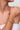 Gold bracelet on a wrist with a neutral background