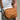 Brown leather bag with 'TODACO' branding worn by a person against a light background