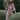 Woman in a patterned dress standing among green bushes
