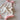 Bloom Pointelle Tie Romper soft cream pointelle knit baby bodysuit featuring adjustable tie shoulders and Cosmos embroidery shown in an angled view.