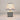 Illuminated Blue Check Table Lamp with a glowing cream fabric shade, gold-tone neck, and a cream ceramic base featuring a dark blue plaid grid.