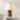 Illuminated view of the Blush resin shade and brass base table lamp displayed on a plinth.