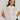 Carrie Zip Top knitted from 100% Pima cotton in an open stitch featuring a half-zip funnel neck and relaxed fit in cream shown in a front studio view.