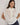 Carrie Zip Top knitted from 100% Pima cotton in an open stitch featuring a half-zip funnel neck and relaxed fit in cream shown in a front studio view.