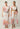 Two models wearing the Cattleya linen maxi dress in Nautilus Bloom print featuring hand-smocked detailing and petal sleeves.
