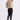 Woman wearing a beige fluffy jacket, black pants, and black knee-high boots on a white background