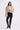 Woman wearing a beige fluffy jacket, black pants, and black boots on a white background