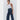 Woman wearing a white tank top and dark blue jeans on a white background