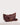 Crescent Sling in warm maple waxy leather featuring a spacious silhouette, clean lines, double zip closure, and antique brass-toned hardware.