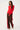 Woman wearing a red sweater and brown pants with red stripes on a white background
