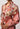 Patterned flower dress with long sleeves and a belt on a plain background