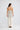 Full-length back view of a model wearing the Elsbeth Top in Ivory Spot showcasing its straight back neckline and low hip length.