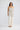 Full-length front view of a model wearing the Elsbeth Top in Ivory Spot paired with cream wide-leg trousers.