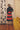Woman in a navy and red stripe skirt in a room with a yellow couch and abstract art on the wall.