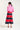 Woman wearing a pink jacket and red and navy striped skirt on a white background