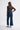 Person wearing blue jeans and a brown long-sleeve top on a white background