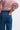 Person wearing a pink sweatshirt and blue jeans on a white background