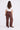 Woman wearing brown wide-leg pants and a white top on a white background