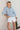 Joanne Shirt Blue lifestyle outdoor view crafted from soft cotton with a pop-over silhouette, drawstring V-neckline, and puffed three-quarter sleeves.