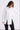 Woman wearing a white button-up shirt and black pants on a white background