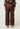 Brown satin pants worn by a person on a white background