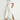 Full length side profile view of a model wearing the Legacy Dress in elm white, showcasing the midi length silhouette, button-through styling with antique brass buttons, and side slit detail.