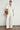Full length front view of a model wearing the Magnify Top in Elm white denim, styled with a relaxed fit, short balloon sleeves, and a gathered front yoke.