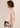Woman wearing a beige sweater with a plain background